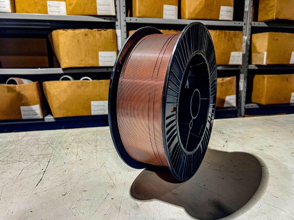 Bobina de arame para solda exposta em bancada, usada para demonstrar visualmente qual melhor arame para solda MIG em oficinas e indústrias.