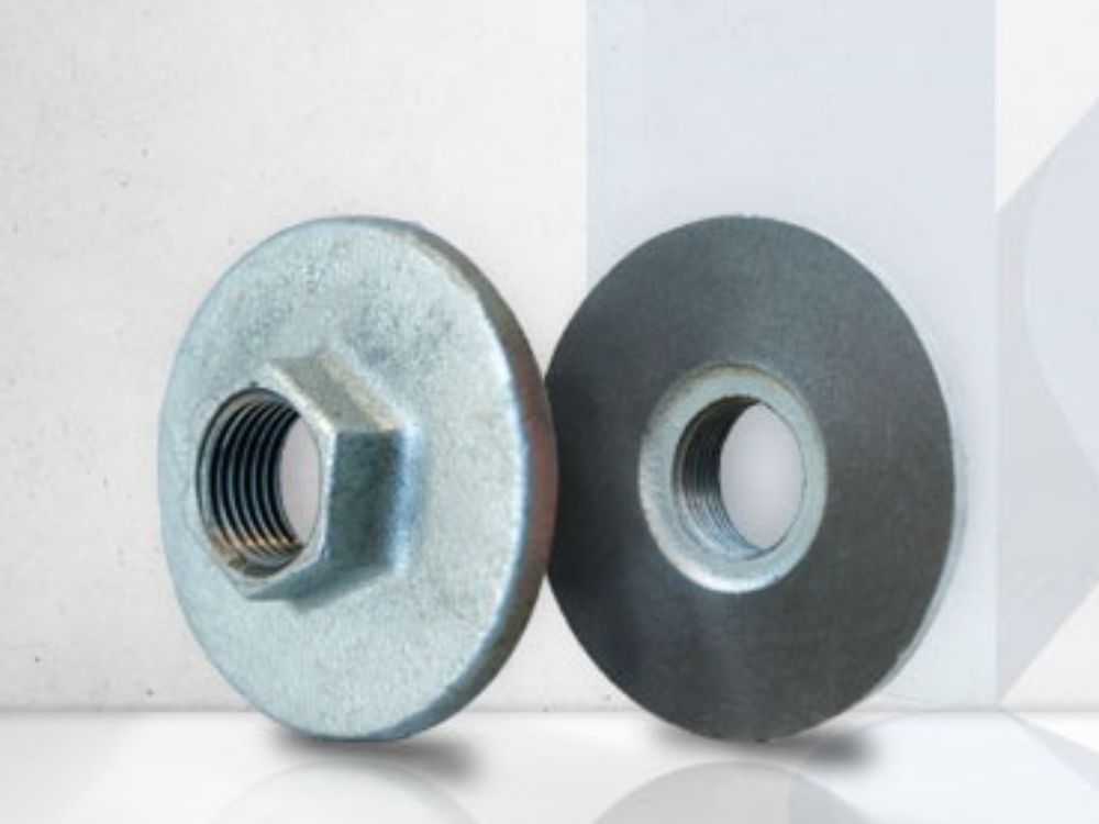 Duas porcas flangeadas metálicas com rosca interna, utilizadas para fixação segura em superfícies planas ou estruturas metálicas.