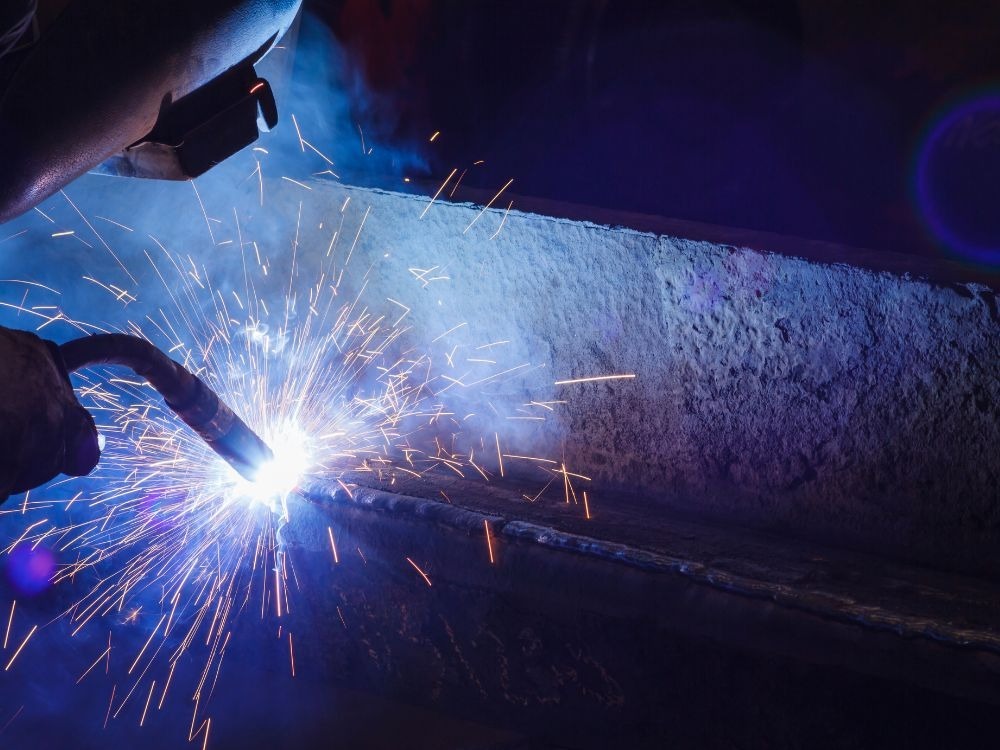 Solda em metal bruto com forte emissão de faíscas, representando resistência e desempenho que indicam que a solda MIG é boa.