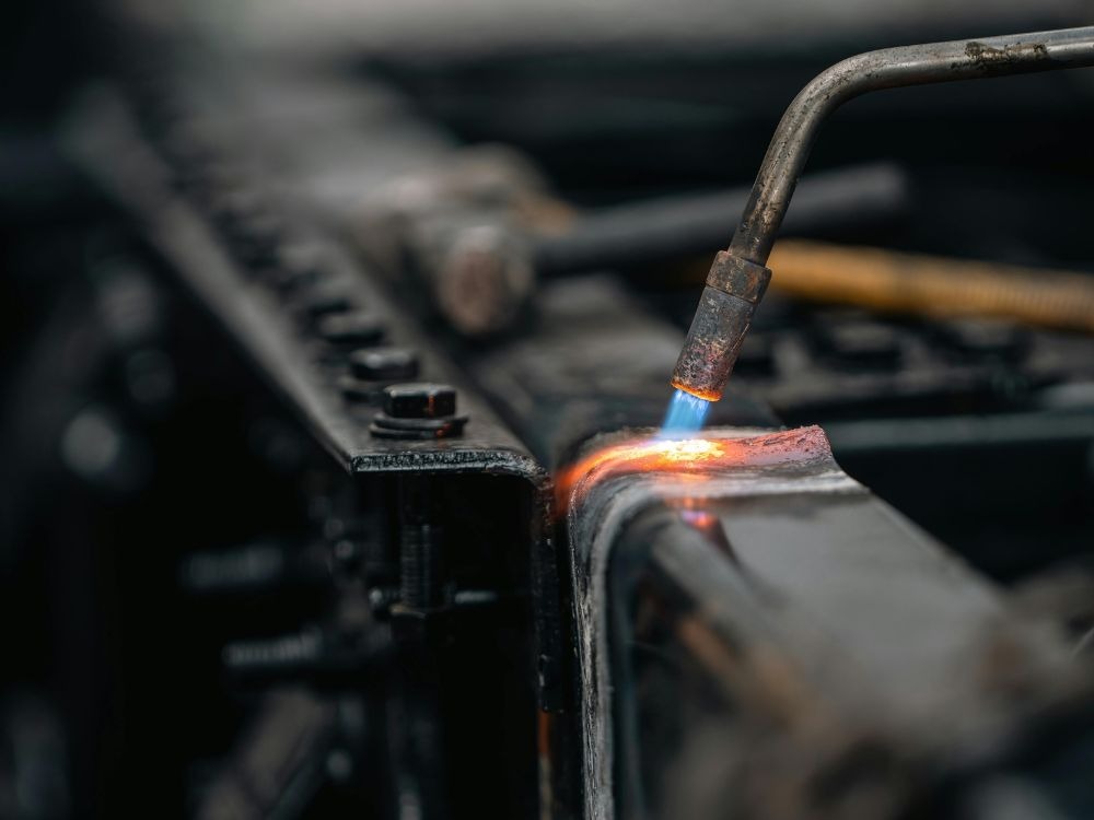 Detalhe da chama e do bico de solda atuando sobre o metal, representando Qual gás usa na solda MIG: em processos de aquecimento e fusão controlada.