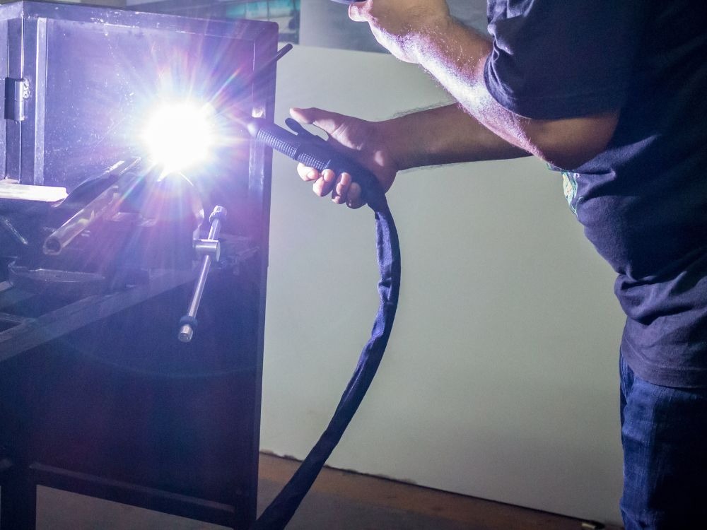 Processo de soldagem industrial com arco elétrico intenso, ilustrando Qual gás usa na solda MIG: durante aplicações em ambientes metalúrgicos.