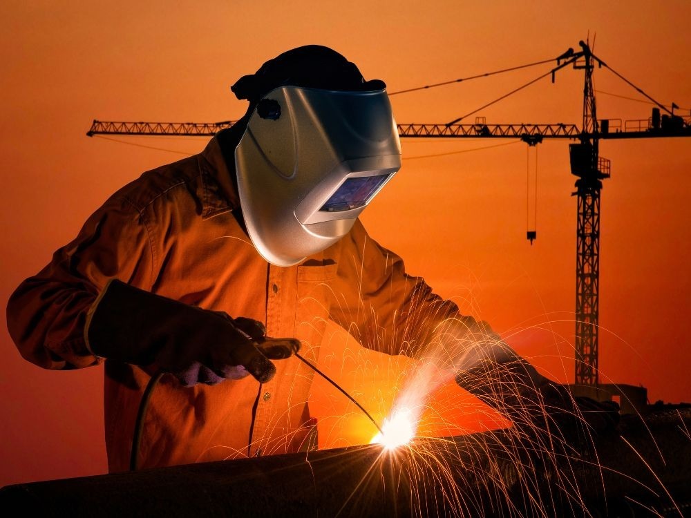 Soldagem em obra externa ao entardecer representando a diferença entre solda MIG e MAG em grandes estruturas metálicas.