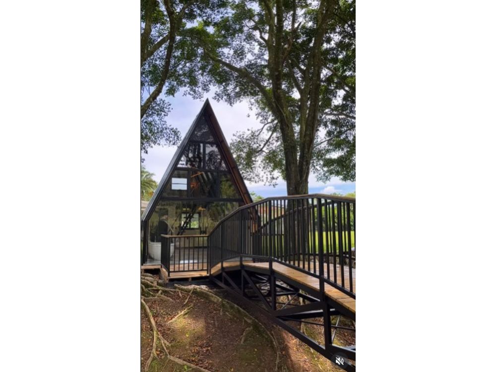 Casas com estrutura metálica em modelo A-frame, com passarela elevada e integração à natureza.