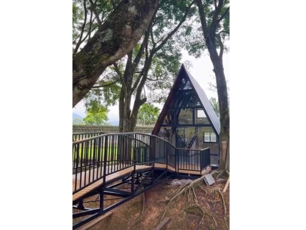 Casas com estrutura metálica em modelo A-frame, com passarela elevada e integração à natureza.