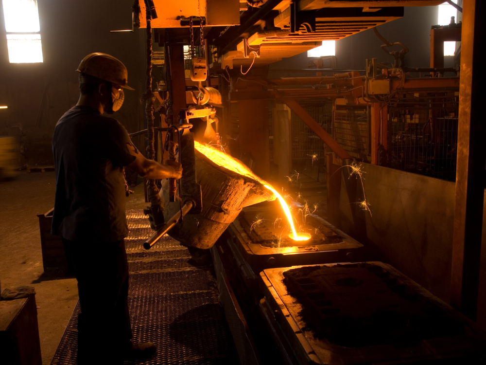 Metal em estado líquido sendo despejado durante uma operação industrial, ilustrando uma etapa de transformação siderúrgica.