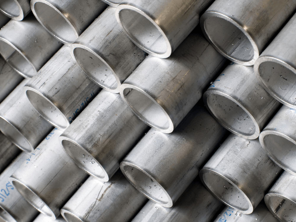 Conjunto de tubos metálicos cilíndricos empilhados, com extremidades circulares visíveis e superfícies prateadas em close.