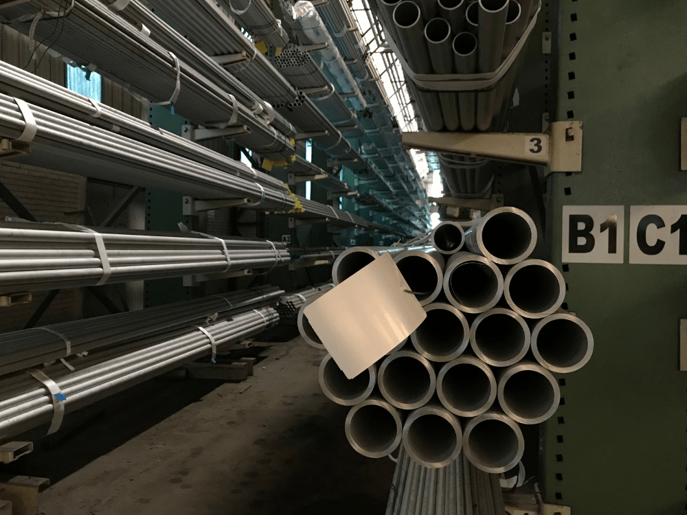 Tubos metálicos de diferentes diâmetros organizados em prateleiras industriais, ilustrando produtos utilizados em aplicações com aço carbono. Tudo para explicar o que é aço carbono.